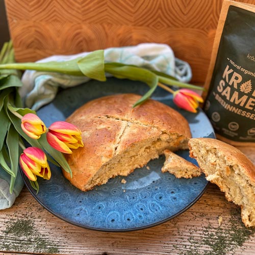 Ein Osterbrot liegt auf einem Teller neben Tulpen