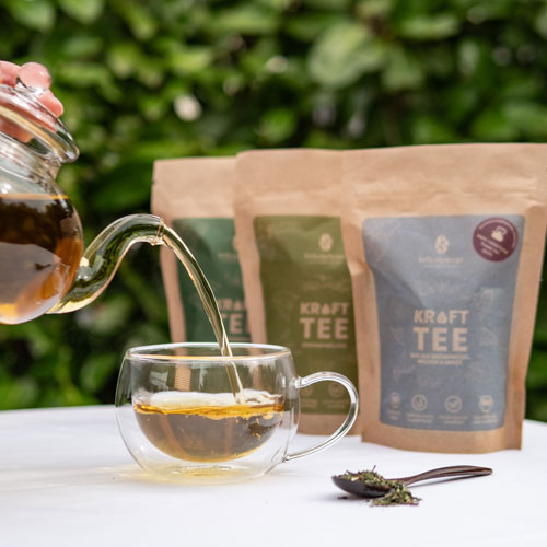 Kräutertee wird vor den Beuteln in eine Tasse gegossen