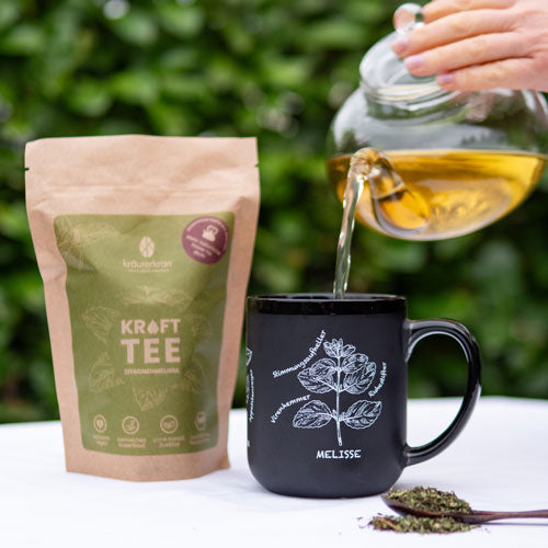 Kräutertee wird aus einer Teekanne in eine Tasse gegossen